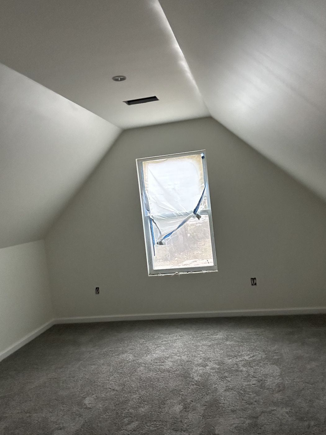 Gray carpet in an upstairs room with sloped ceilings and a window