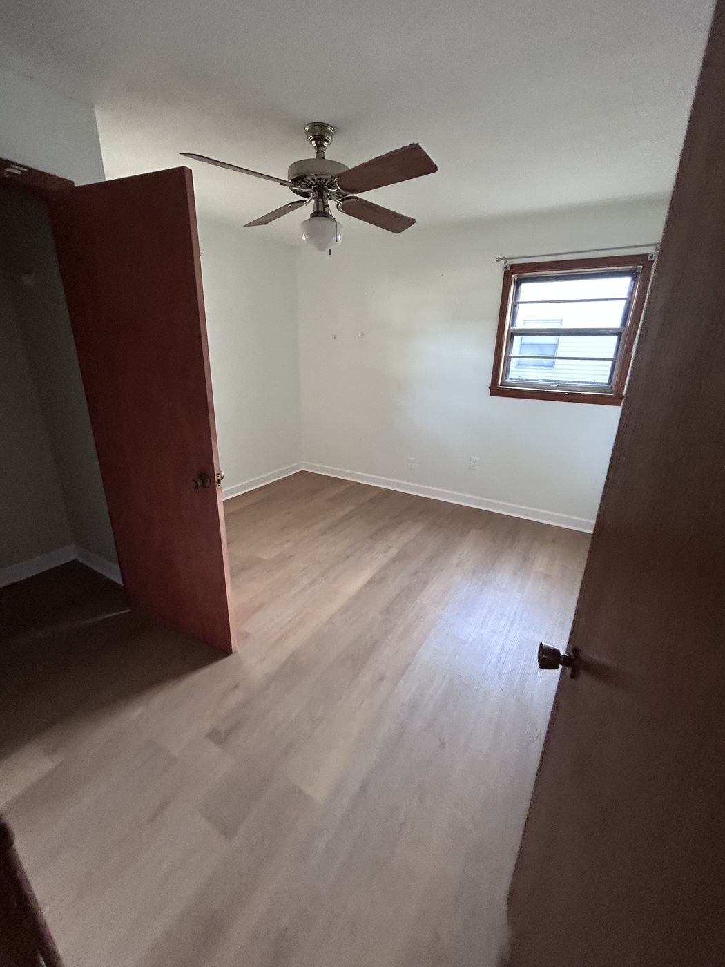 Room with a ceiling fan and gray-brown plank-style flooring